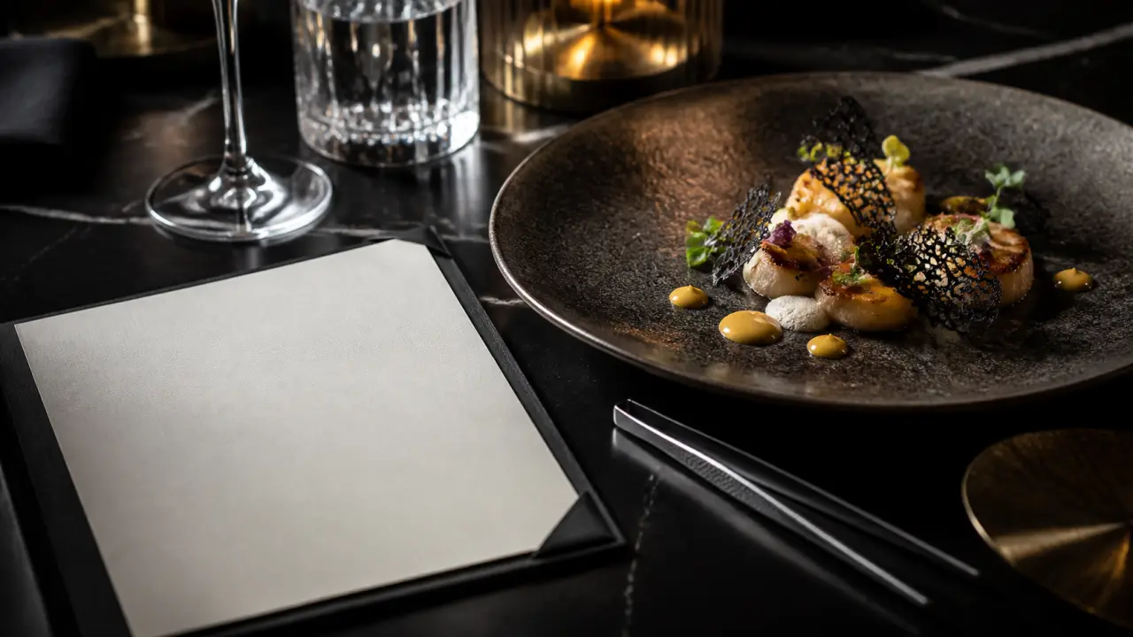 Plat gastronomique étoilé en clair-obscur, sauce brillante et herbes délicates